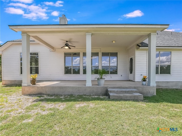 rear view of house featuring ceiling fan and a yard