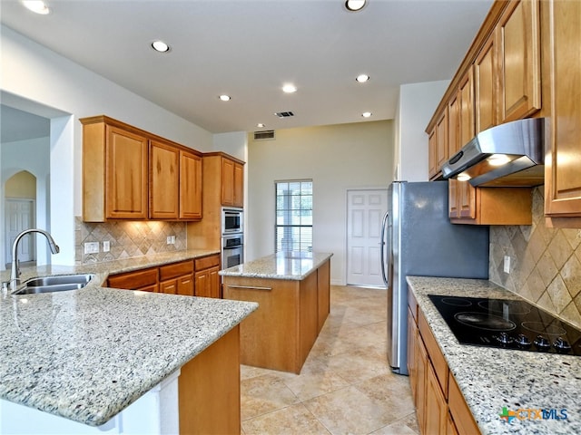 kitchen featuring a center island, sink, ventilation hood, light stone countertops, and appliances with stainless steel finishes