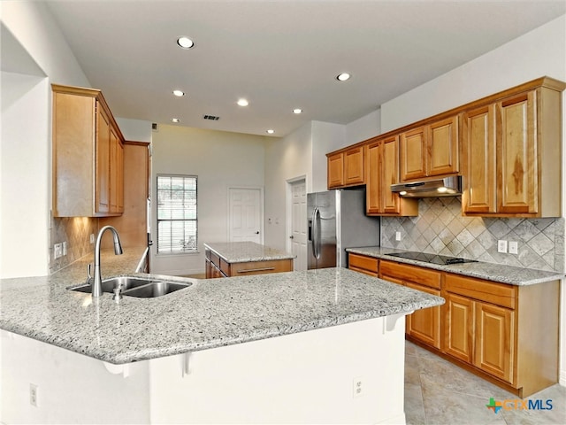 kitchen with stainless steel fridge with ice dispenser, light stone countertops, sink, a breakfast bar area, and kitchen peninsula