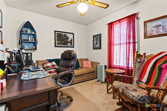 carpeted office with ceiling fan and radiator heating unit