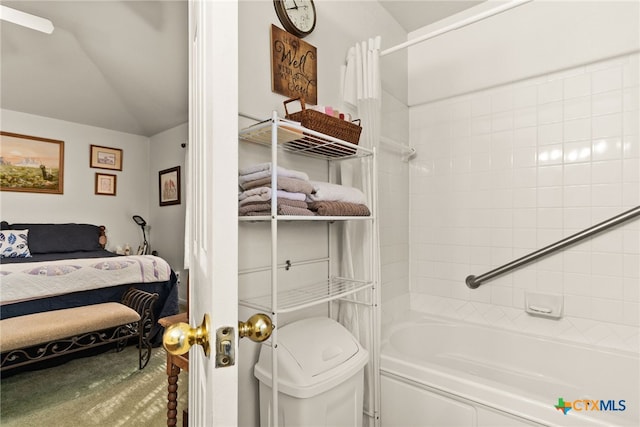 bathroom with vaulted ceiling and tiled shower / bath