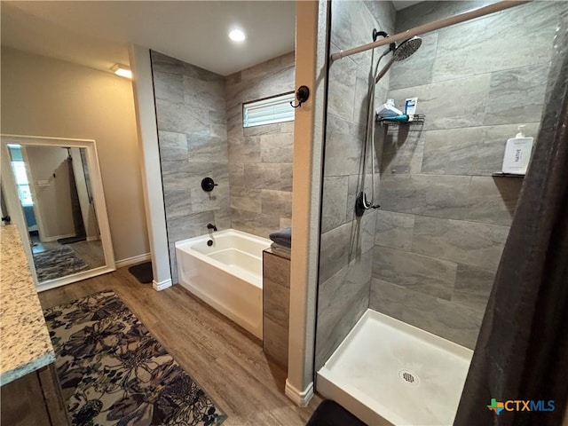 bathroom with tiled shower, baseboards, a garden tub, and wood finished floors