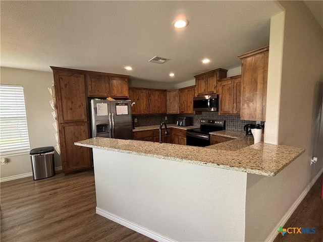 kitchen featuring visible vents, appliances with stainless steel finishes, baseboards, a peninsula, and dark wood-style floors