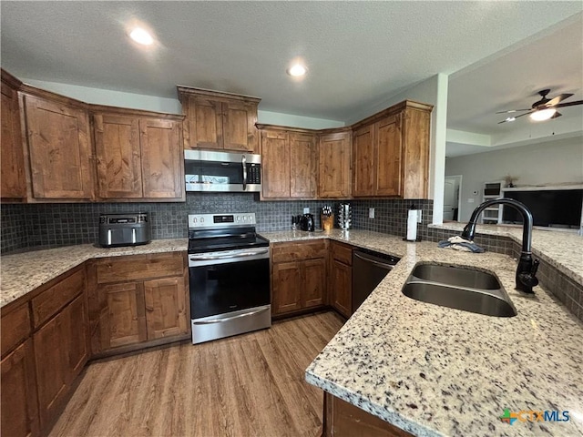 kitchen with a sink, backsplash, stainless steel appliances, and light wood-type flooring
