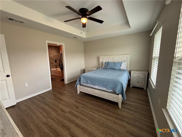 bedroom with visible vents, a raised ceiling, baseboards, and wood finished floors