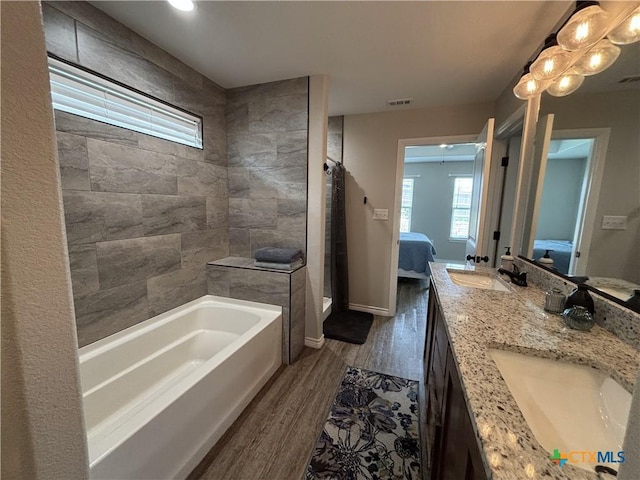 full bath with a sink, a bath, ensuite bathroom, and wood finished floors