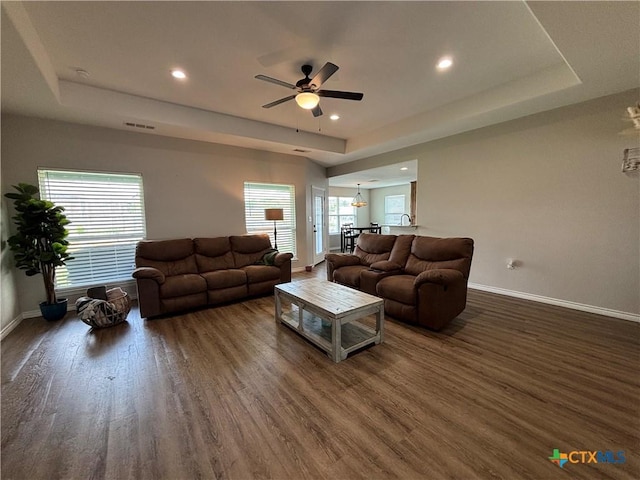living room featuring baseboards, a ceiling fan, a raised ceiling, and wood finished floors