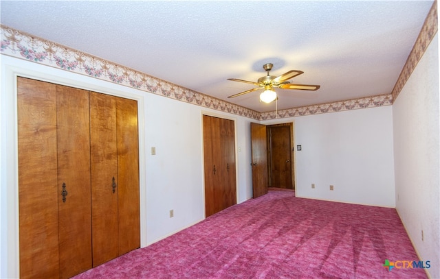 unfurnished bedroom featuring two closets, ceiling fan, carpet floors, and a textured ceiling