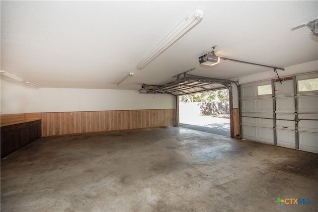 garage with wood walls and a garage door opener