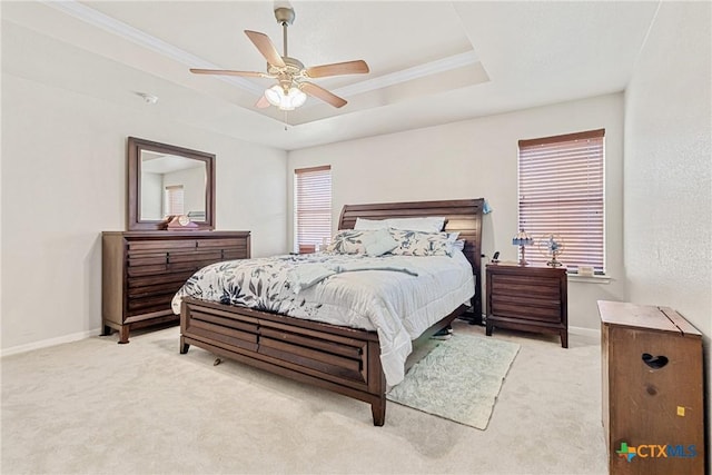 bedroom featuring ceiling fan, light carpet, and a tray ceiling