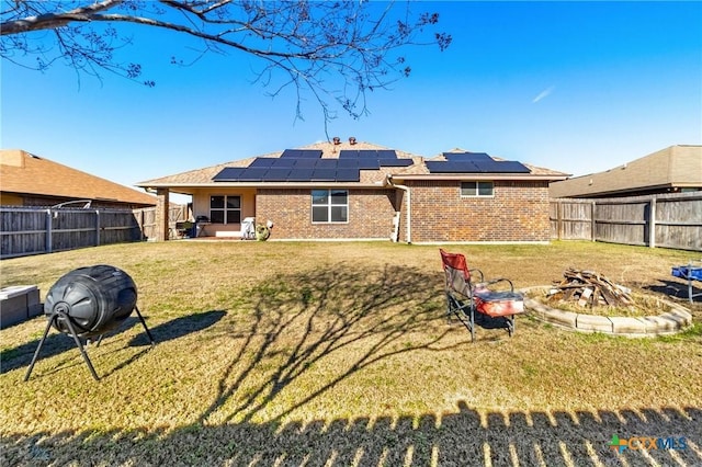 rear view of property featuring solar panels and an outdoor fire pit