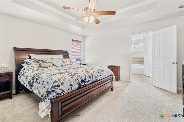 carpeted bedroom featuring a tray ceiling, connected bathroom, ceiling fan, and crown molding