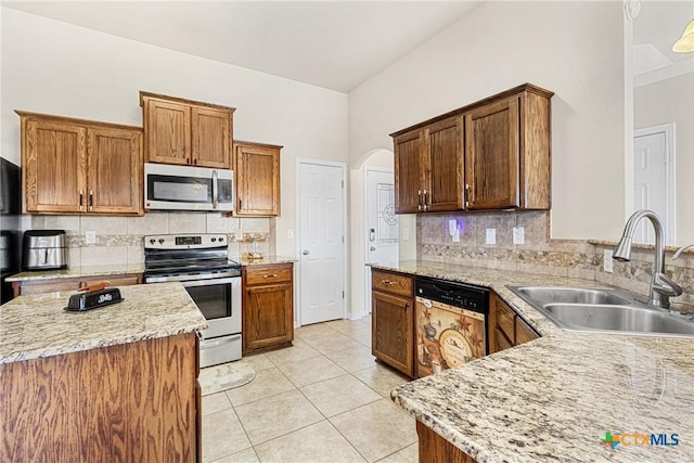 kitchen featuring decorative backsplash, appliances with stainless steel finishes, light stone countertops, and sink