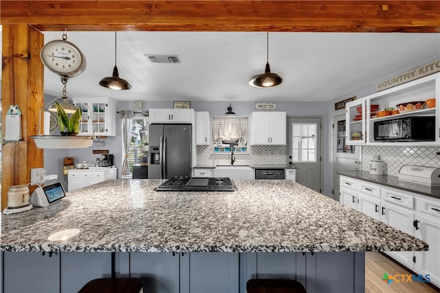 kitchen with white cabinetry, appliances with stainless steel finishes, decorative light fixtures, a kitchen bar, and light hardwood / wood-style floors