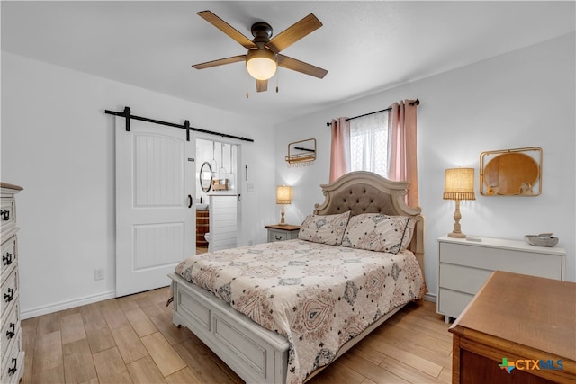 bedroom featuring light wood-type flooring, a barn door, and ceiling fan