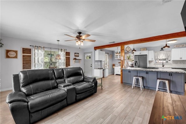 living room with light hardwood / wood-style floors, ceiling fan, and sink