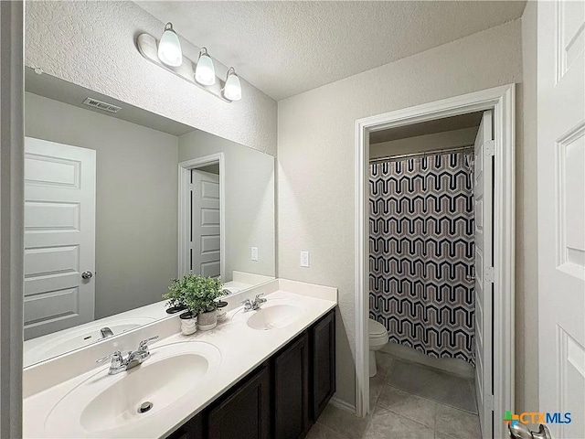 bathroom featuring toilet, vanity, tile patterned flooring, and a textured ceiling