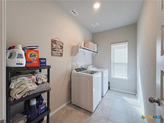 clothes washing area with independent washer and dryer and light tile patterned floors