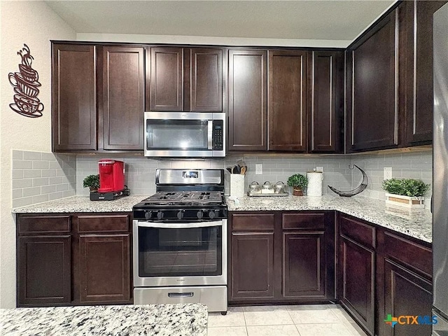 kitchen with appliances with stainless steel finishes, dark brown cabinetry, and light stone counters