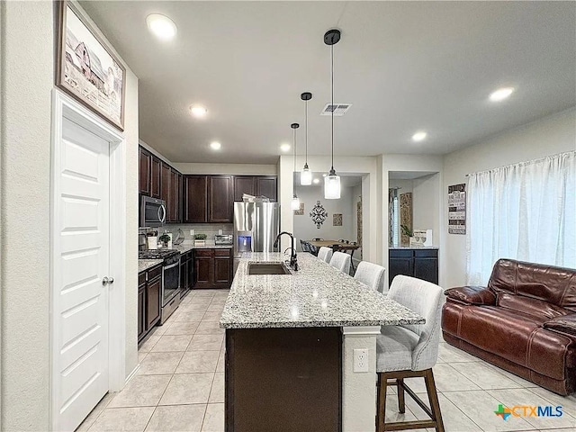 kitchen featuring appliances with stainless steel finishes, a kitchen breakfast bar, decorative light fixtures, sink, and a kitchen island with sink