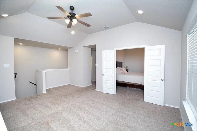 unfurnished bedroom featuring vaulted ceiling, light colored carpet, and ceiling fan