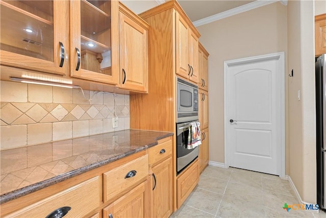 kitchen featuring appliances with stainless steel finishes, dark stone counters, tasteful backsplash, ornamental molding, and light tile patterned flooring