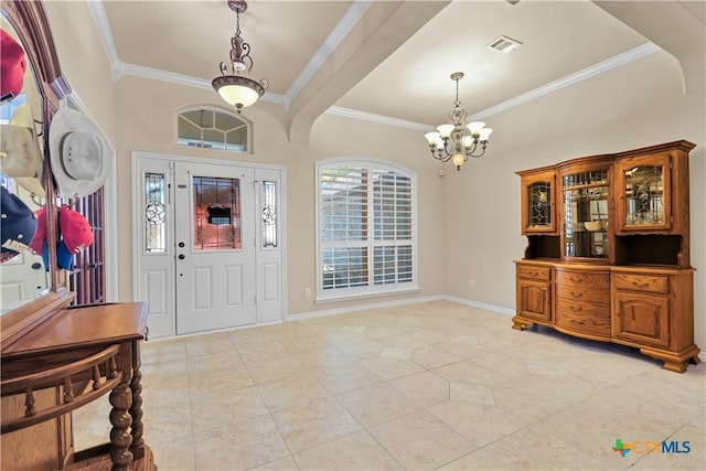 tiled foyer featuring ornamental molding and an inviting chandelier