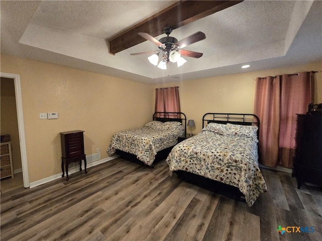 bedroom with baseboards, beam ceiling, wood finished floors, and a raised ceiling