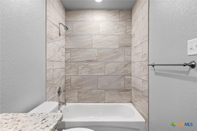 bathroom featuring vanity, bathing tub / shower combination, toilet, and a textured wall