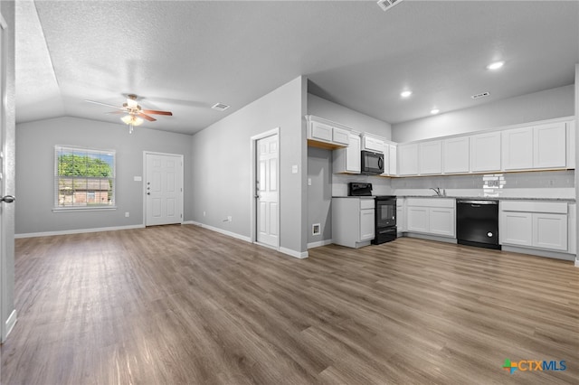 kitchen featuring white cabinetry, light wood-type flooring, black appliances, and vaulted ceiling