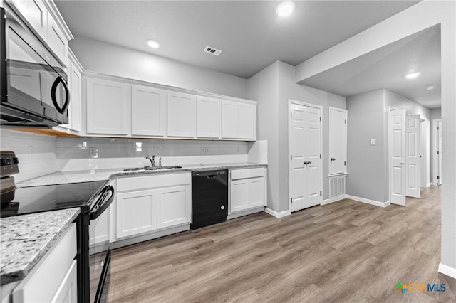 kitchen with visible vents, white cabinets, black appliances, and a sink