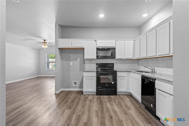 kitchen with white cabinetry, black appliances, sink, and light stone countertops