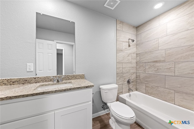 full bath with visible vents, toilet, washtub / shower combination, vanity, and a textured wall