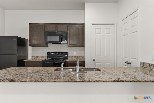 kitchen featuring light stone counters, kitchen peninsula, black appliances, sink, and dark brown cabinets