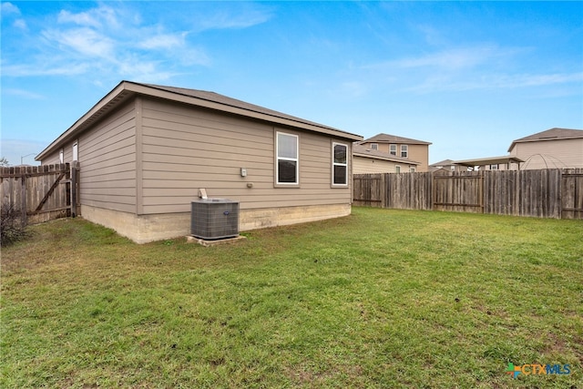 back of property featuring central air condition unit and a yard