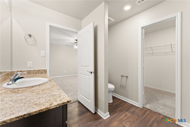 bathroom with wood-type flooring, vanity, toilet, and ceiling fan