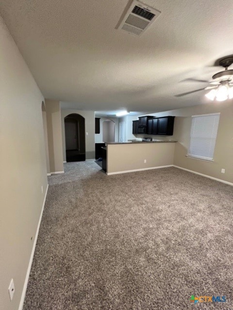 unfurnished living room with carpet flooring, ceiling fan, and a textured ceiling