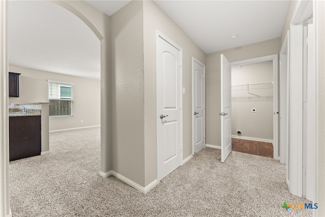 hall with light colored carpet and sink