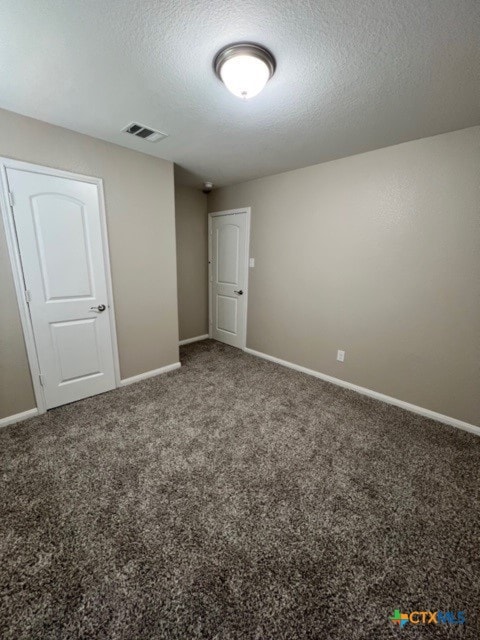 unfurnished room featuring carpet flooring and a textured ceiling