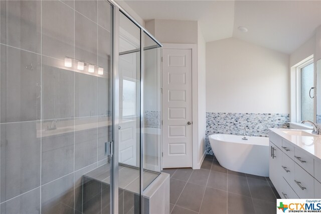 bathroom with lofted ceiling, tile patterned floors, separate shower and tub, tile walls, and vanity