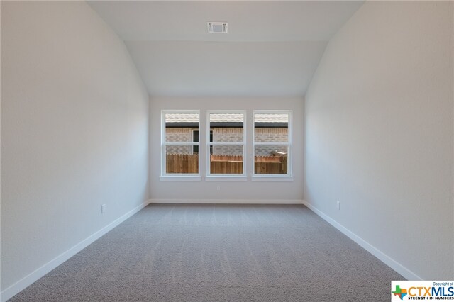 empty room featuring carpet and lofted ceiling