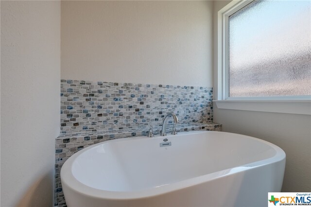 bathroom with a bath and tasteful backsplash