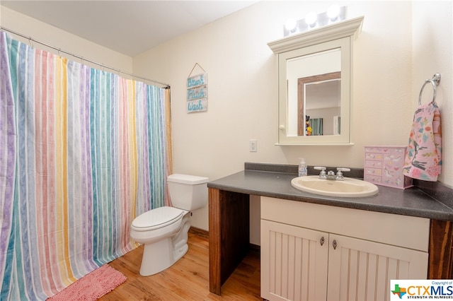 bathroom with hardwood / wood-style floors, vanity, curtained shower, and toilet