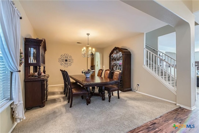 dining room featuring baseboards, a chandelier, wood finished floors, and stairway