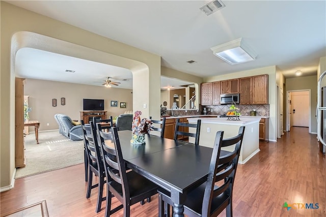 dining space with baseboards, ceiling fan, light wood-style flooring, and visible vents