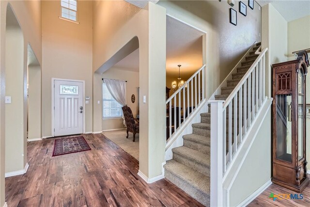 foyer entrance featuring an inviting chandelier, baseboards, stairs, and wood finished floors