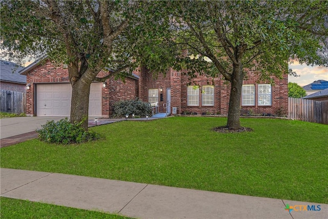 view of property hidden behind natural elements with brick siding, an attached garage, fence, and a front yard