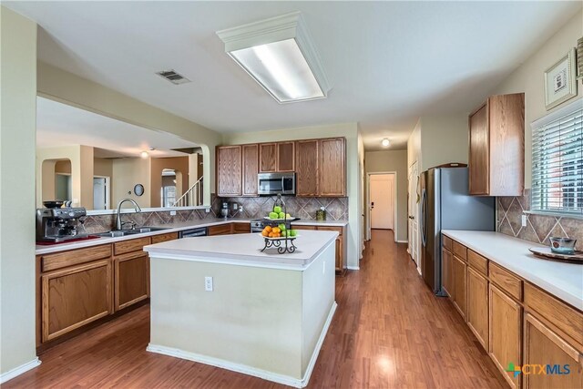 kitchen with a sink, decorative backsplash, stainless steel appliances, and visible vents