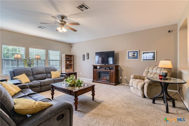 living room with visible vents, carpet flooring, baseboards, and ceiling fan