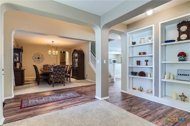 dining room with baseboards, arched walkways, built in features, and wood finished floors